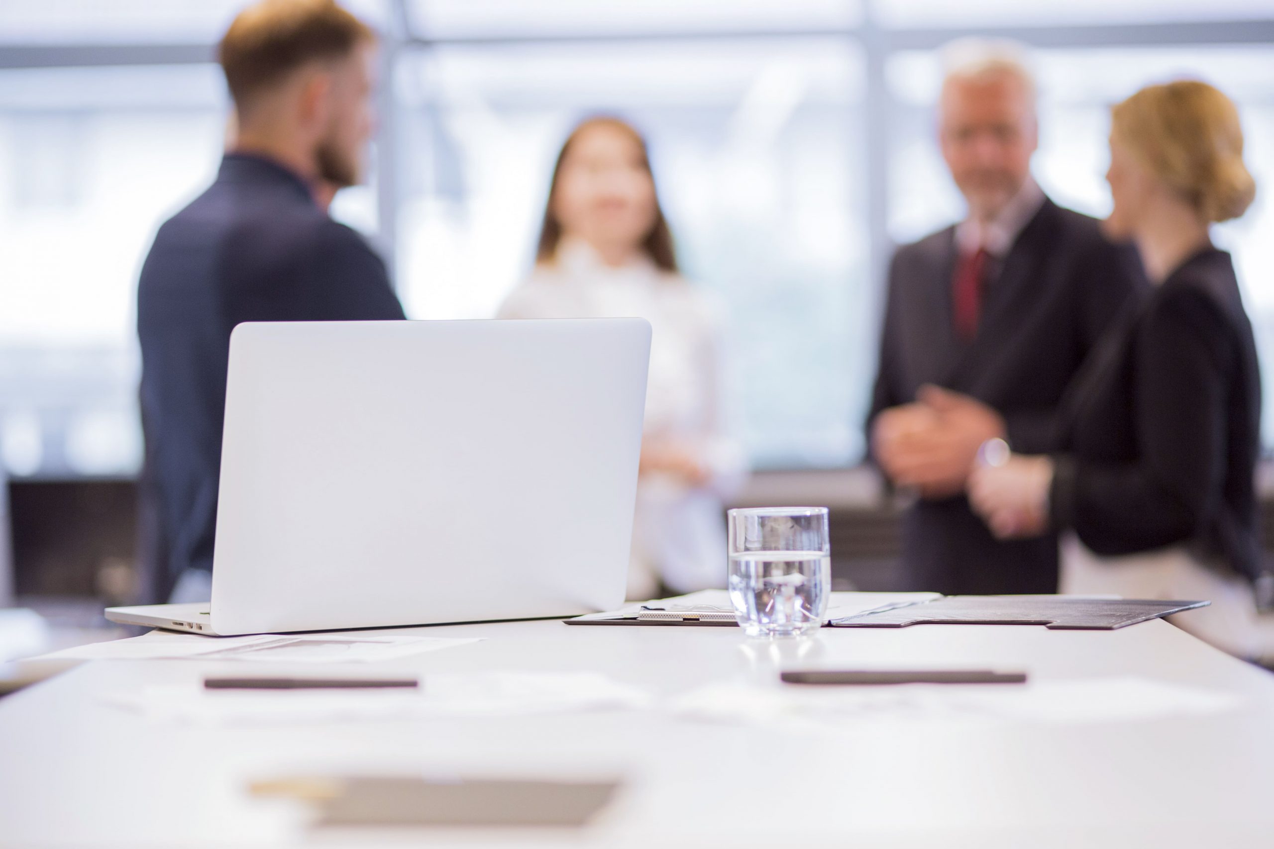 glass-water-with-laptop-table-front-businesspeople-background-2